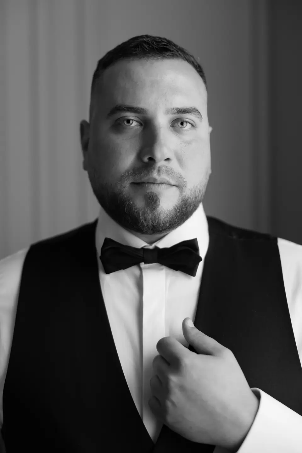 Black and white portrait of Norbert in a bow tie, his hand at his lapel