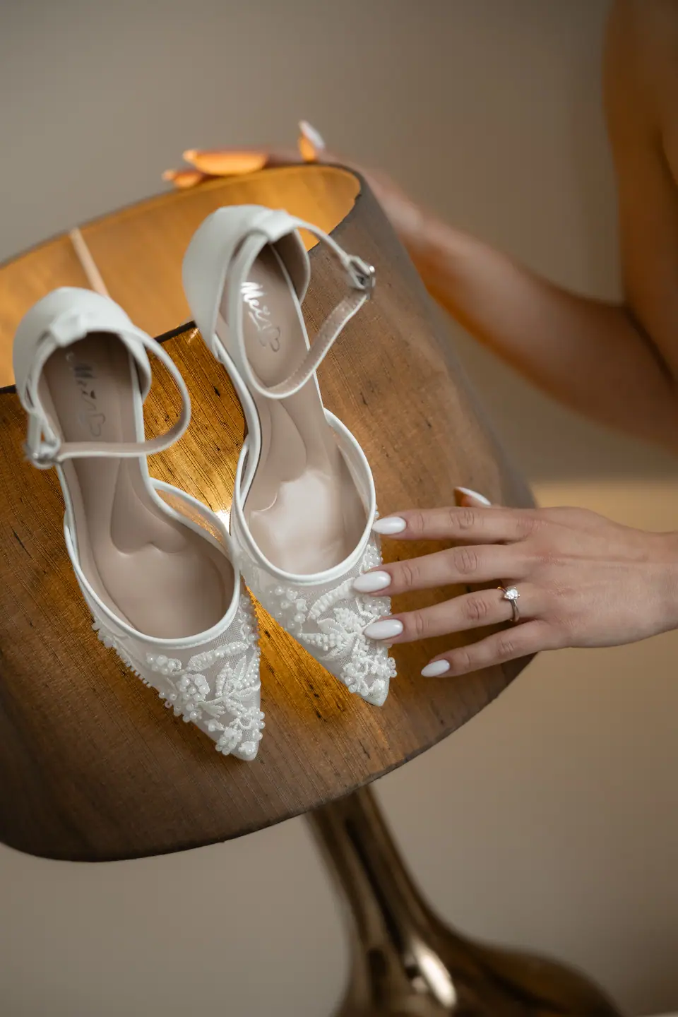 Alexandra’s hand resting beside her beaded shoes on the lamp shade