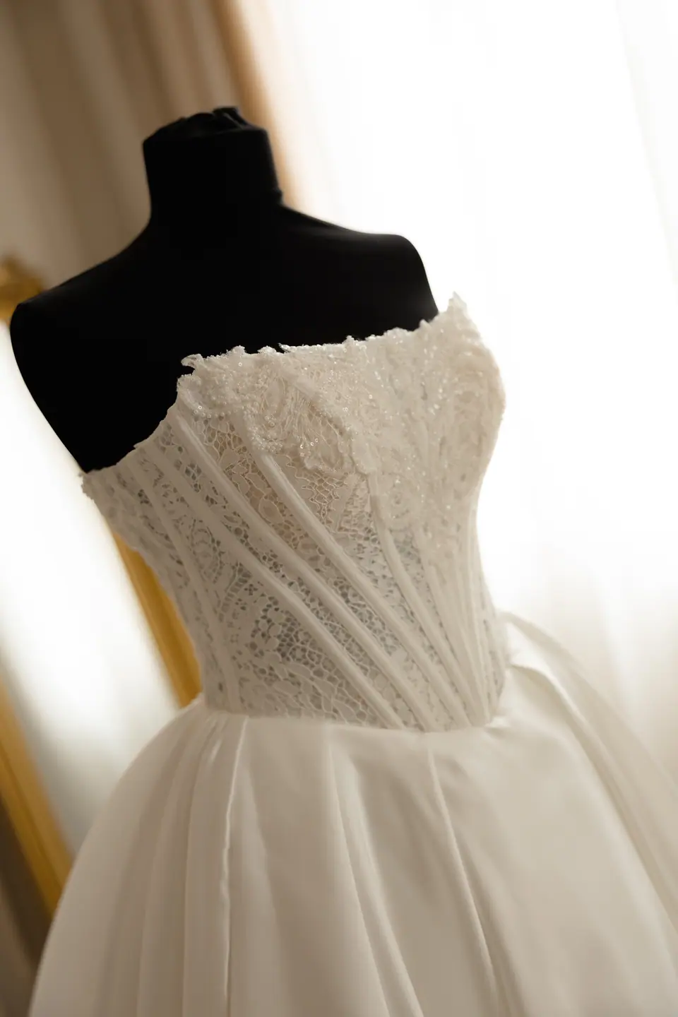 Lace corset bodice of the wedding dress on a mannequin in window light