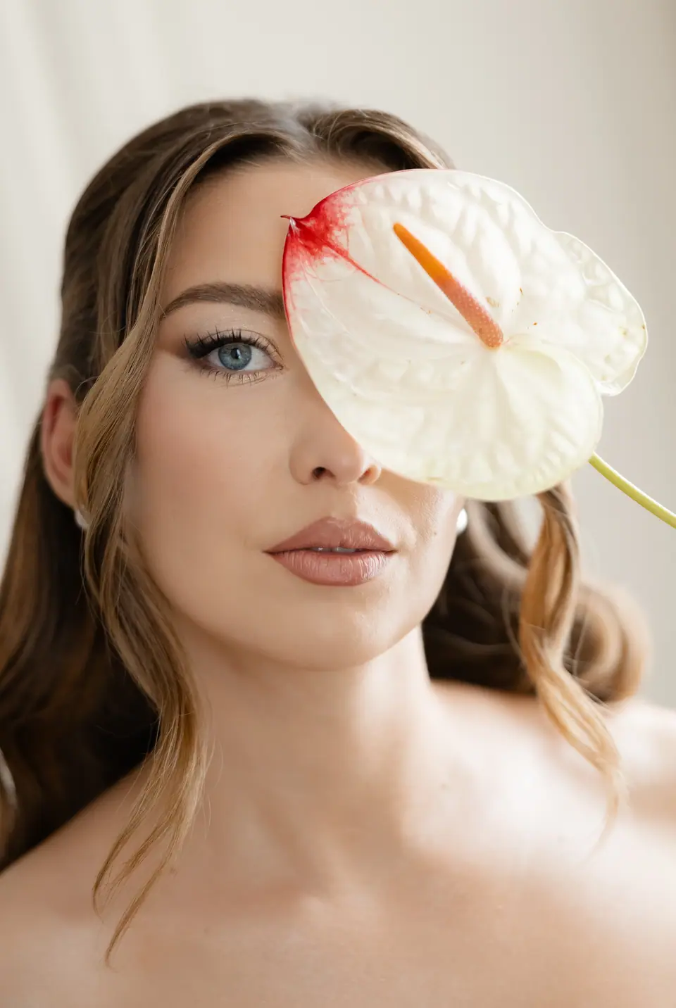 Alexandra holding a white anthurium flower in front of one eye