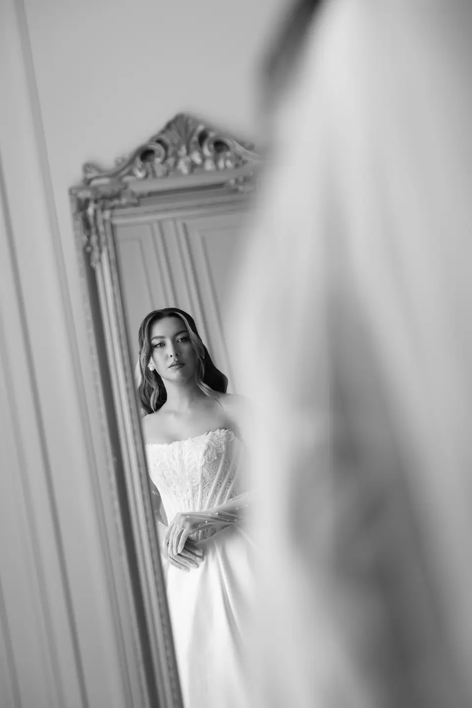 Alexandra seen in a gilded mirror in her wedding dress, in black and white