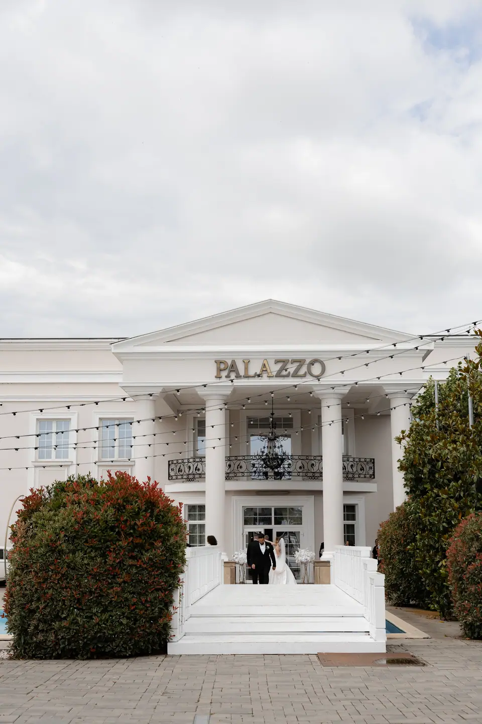Alexandra and Norbert at the top of the entrance steps in front of the white venue