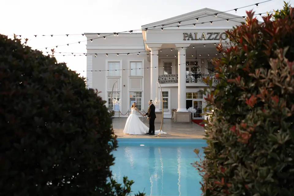 Alexandra and Norbert by the pool in front of the white-columned venue