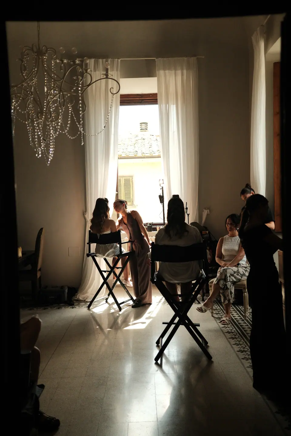 Ana’s make-up being done in a high-ceilinged room at Villa di Ulignano, a chandelier overhead