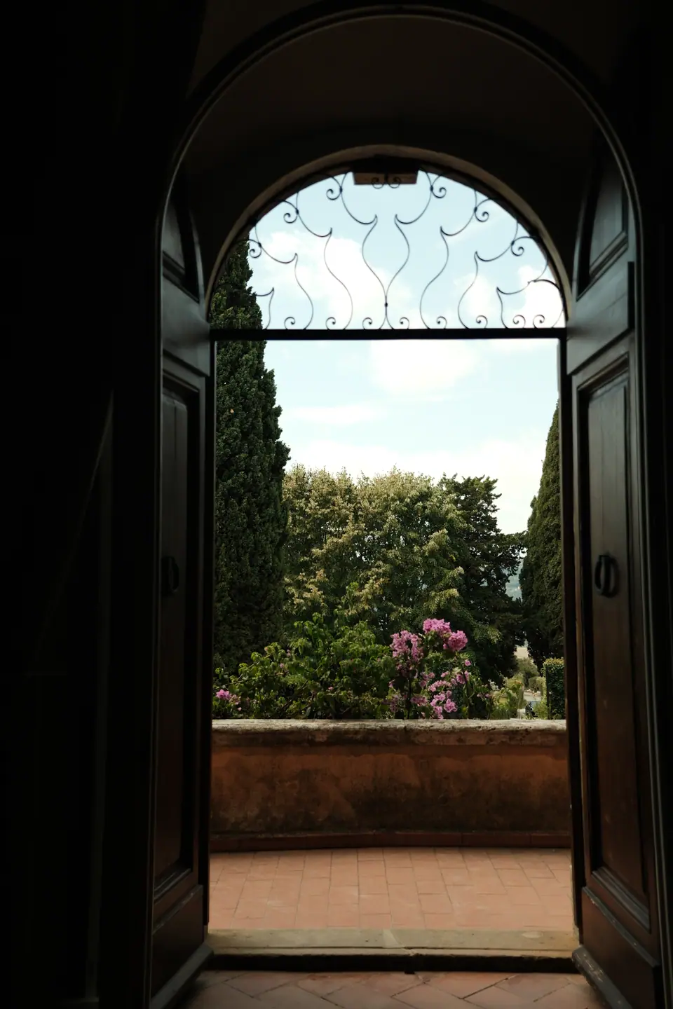 An arched doorway opening onto a terrace of cypresses and flowers