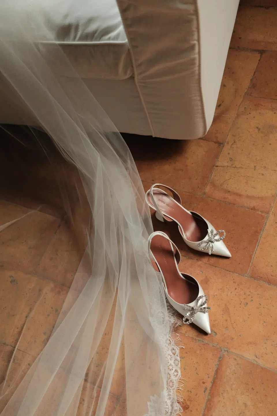Ana’s satin heels with crystal bows resting on the hem of her veil