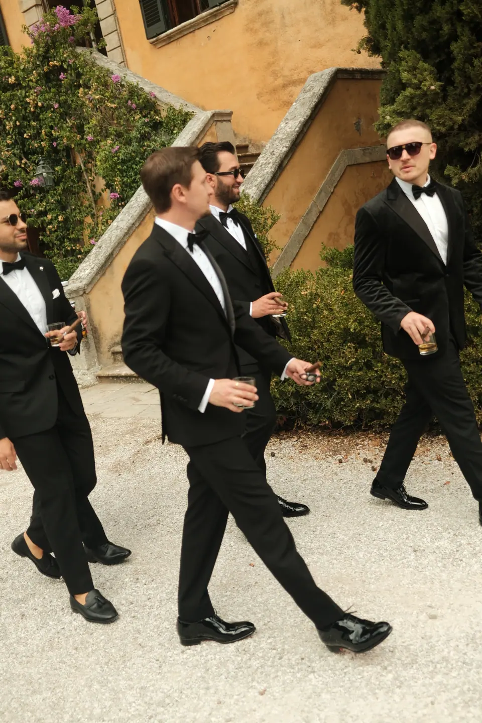 Silviu and his groomsmen walking across the gravel in tuxedos and sunglasses