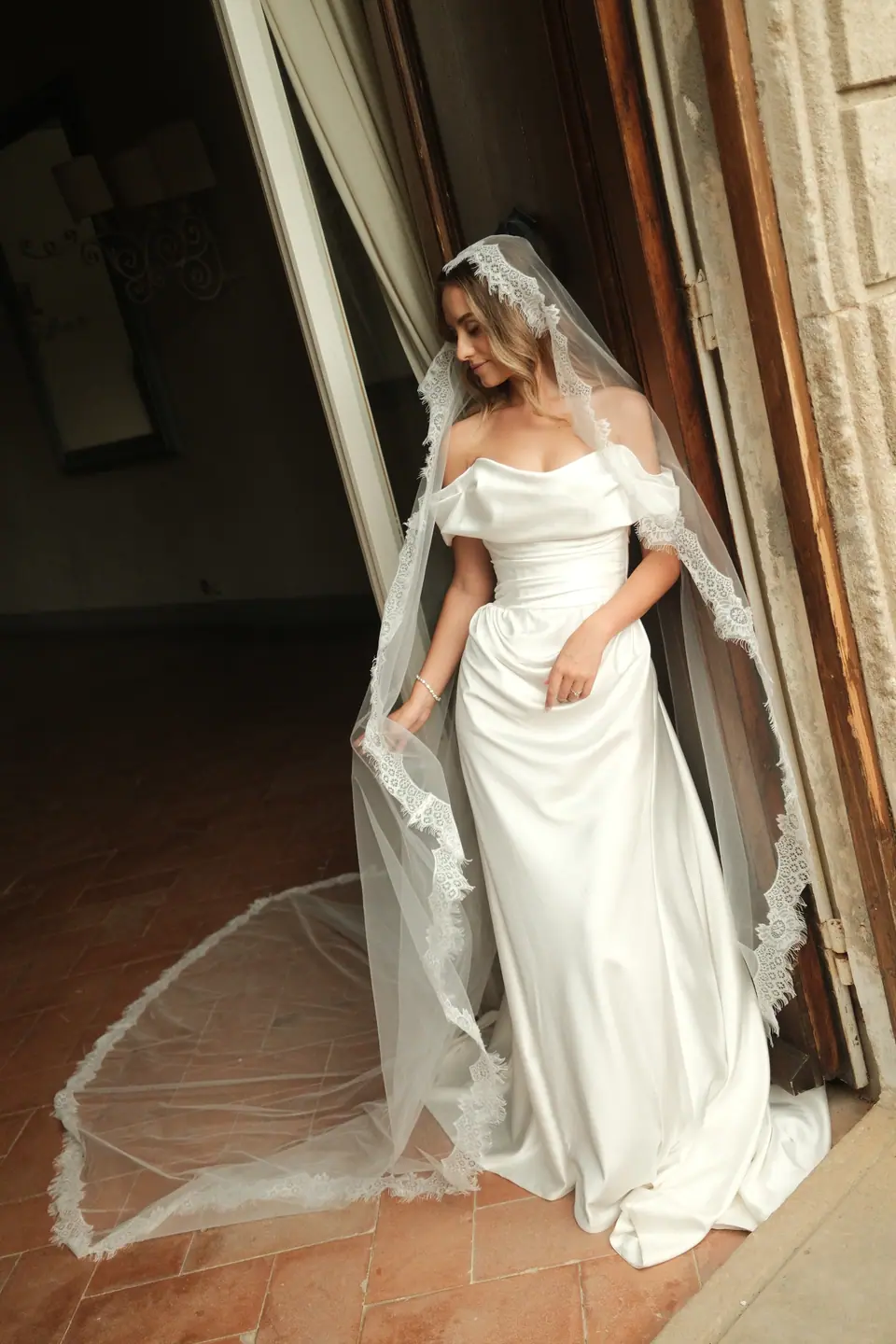Ana stepping through the doorway in her satin gown and long lace veil