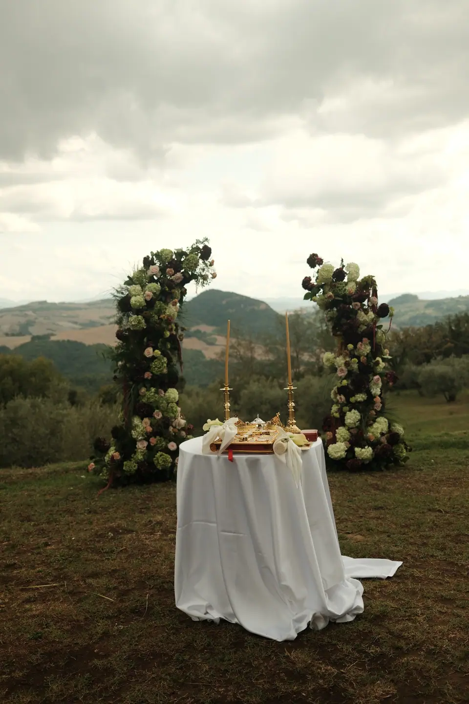 The ceremony table between two floral pillars, the Tuscan hills behind