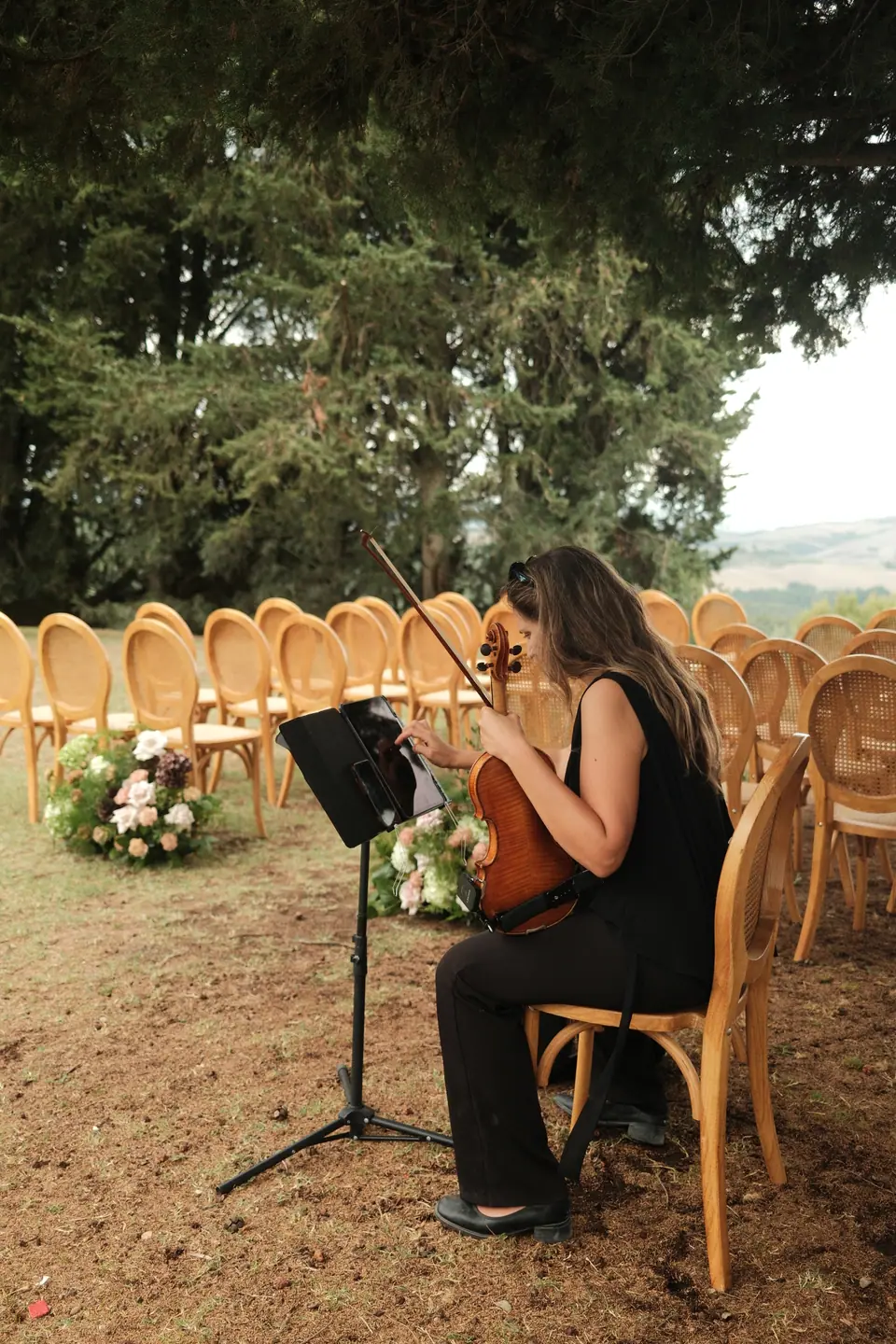 A violinist playing among the rattan chairs as guests arrive