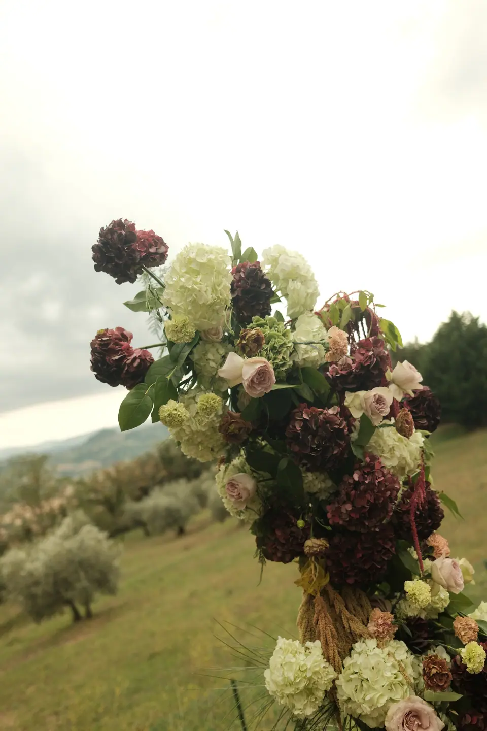 A floral pillar of roses and hydrangeas against the olive groves
