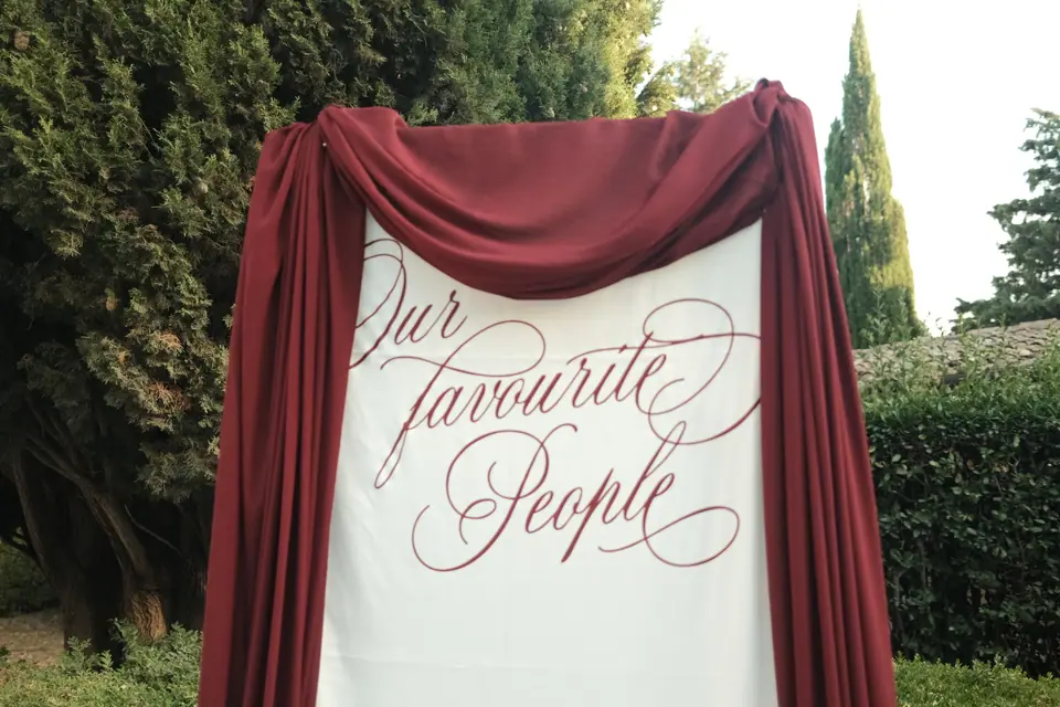 Close-up of the calligraphy seating chart framed in burgundy drapes