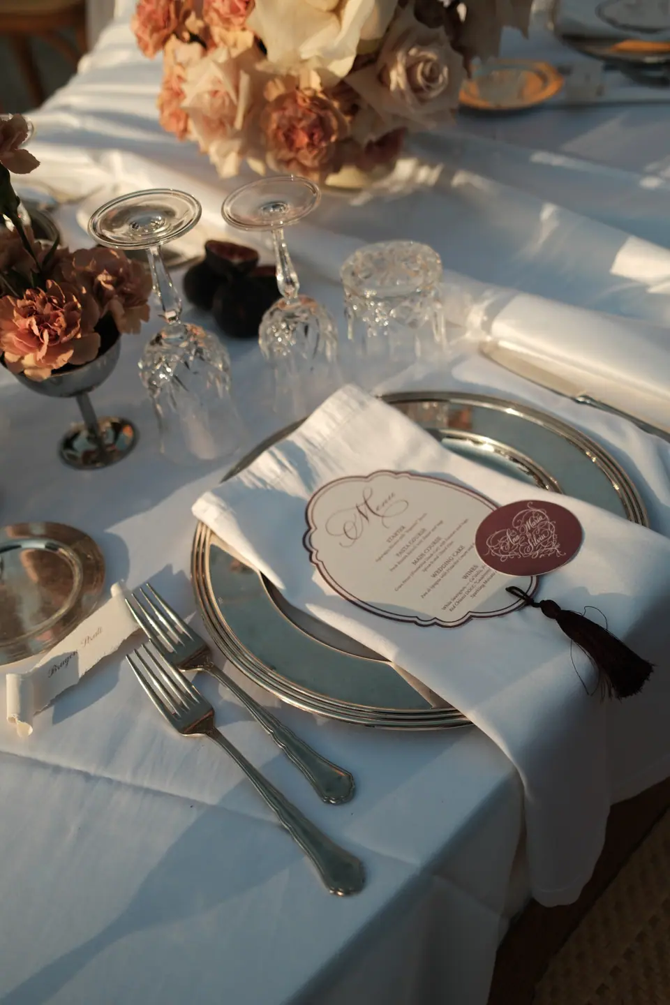 A place setting with a monogrammed menu and a tasselled ribbon
