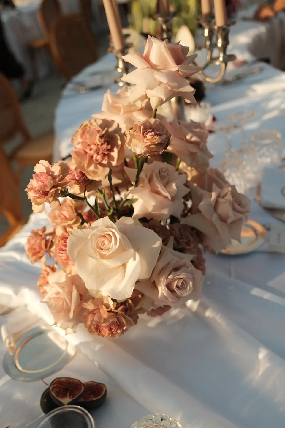 A centrepiece of blush roses and carnations on the dinner table