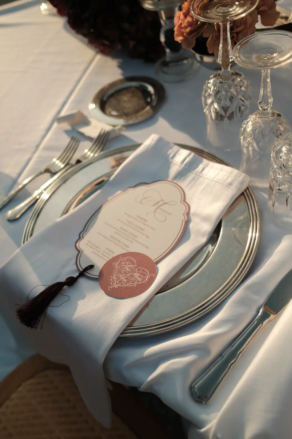 A silver charger and the monogrammed menu at a place setting