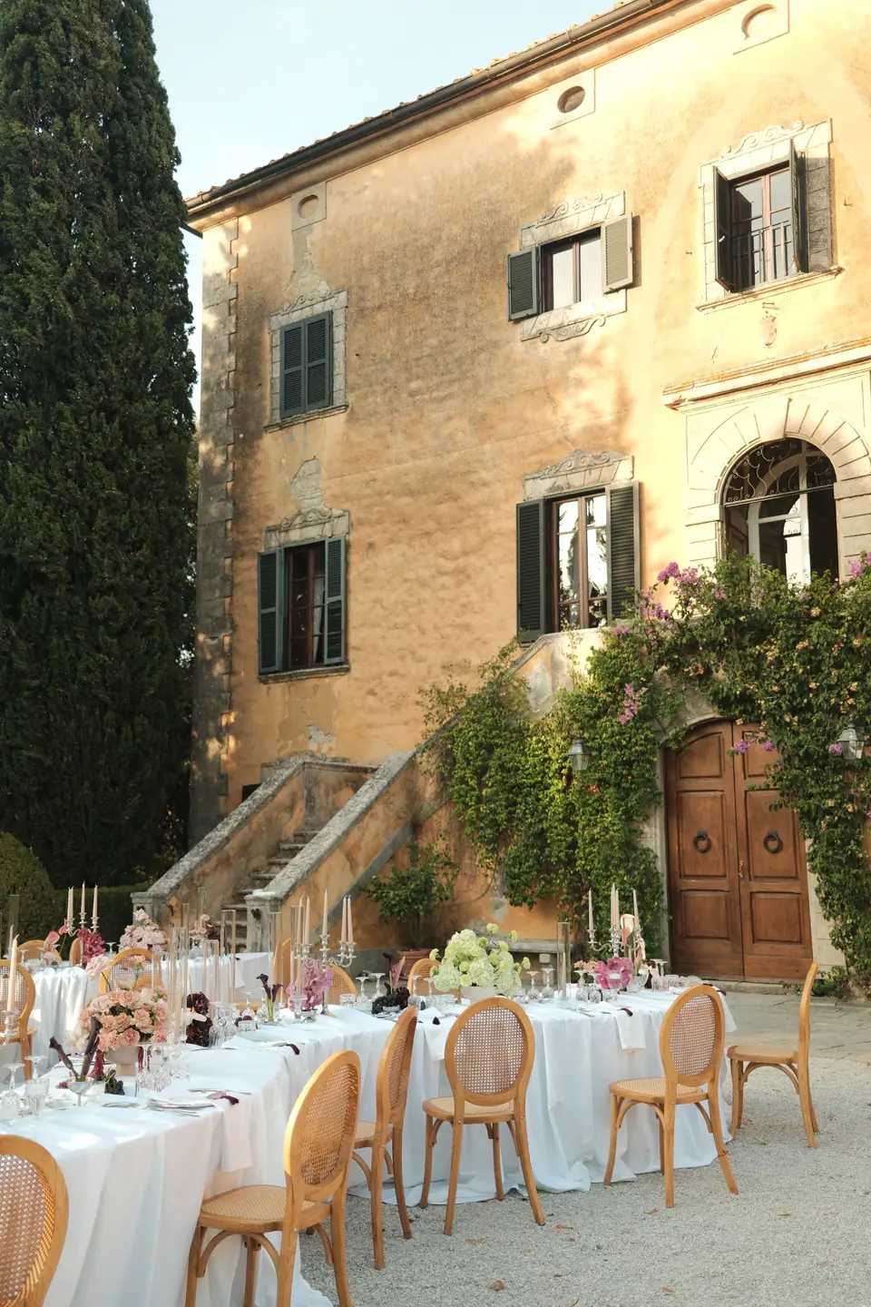 Round dinner tables in the courtyard beneath the villa’s stone steps