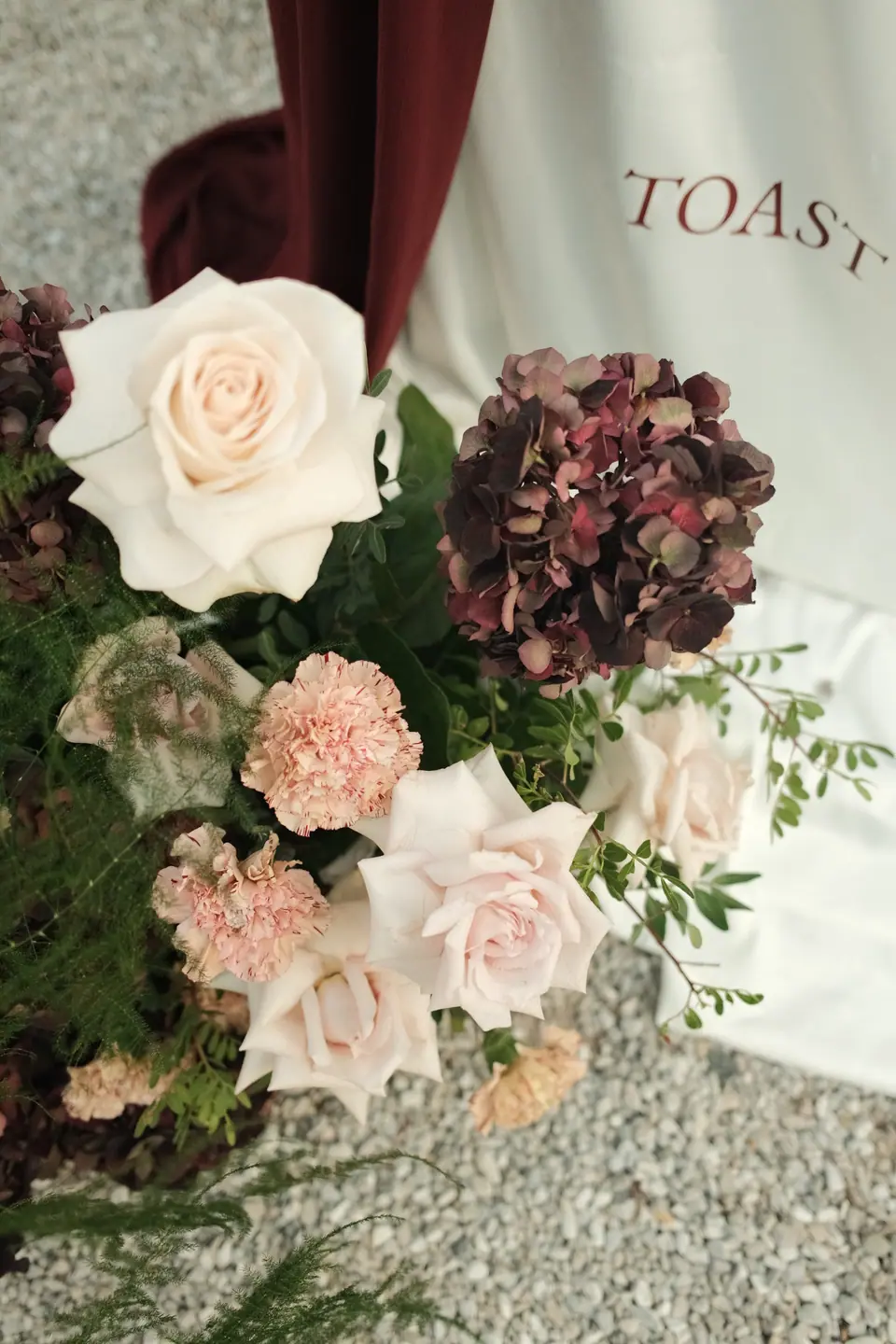 Blush roses and dark hydrangeas beside the “Toast” sign