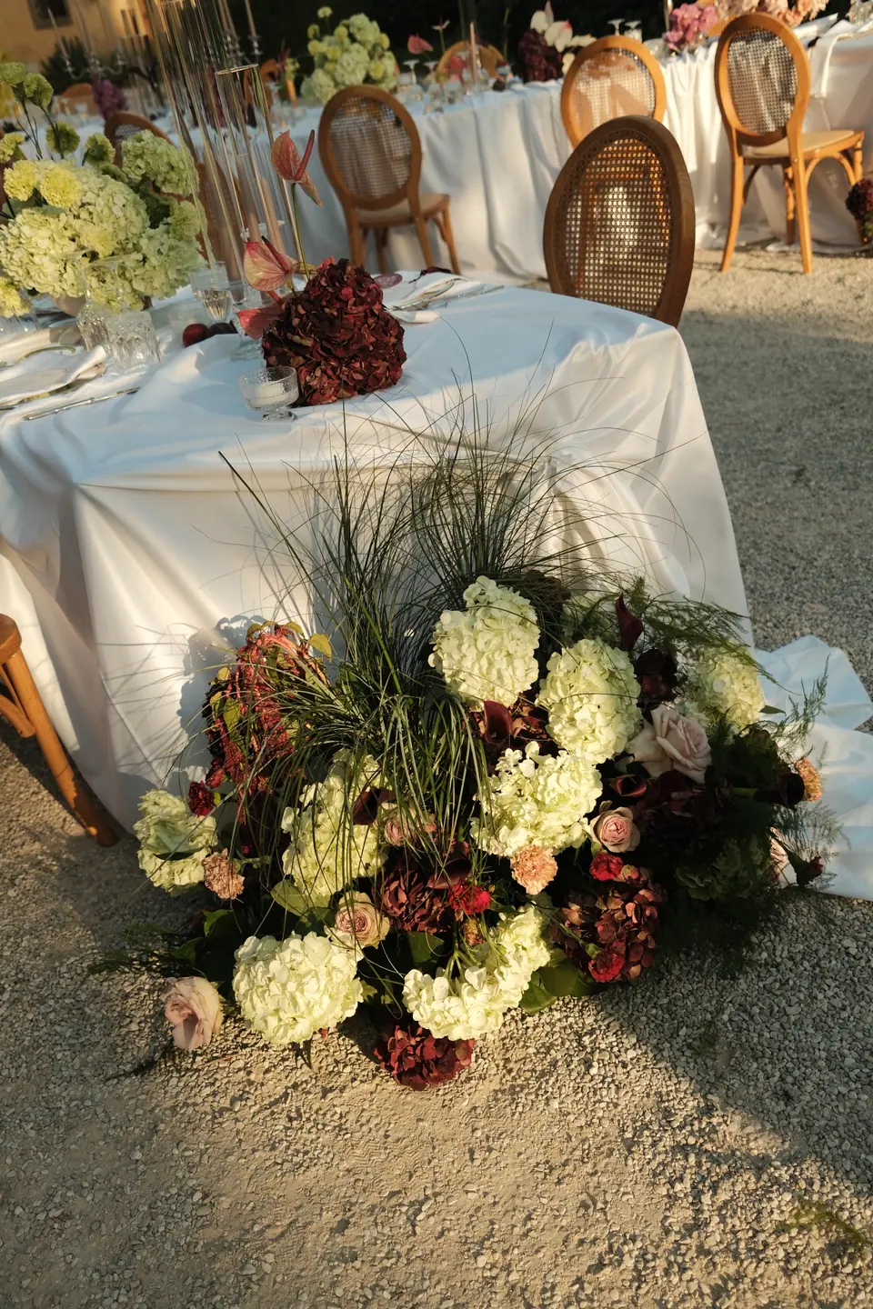 A flower arrangement of hydrangeas and roses at the foot of a dinner table