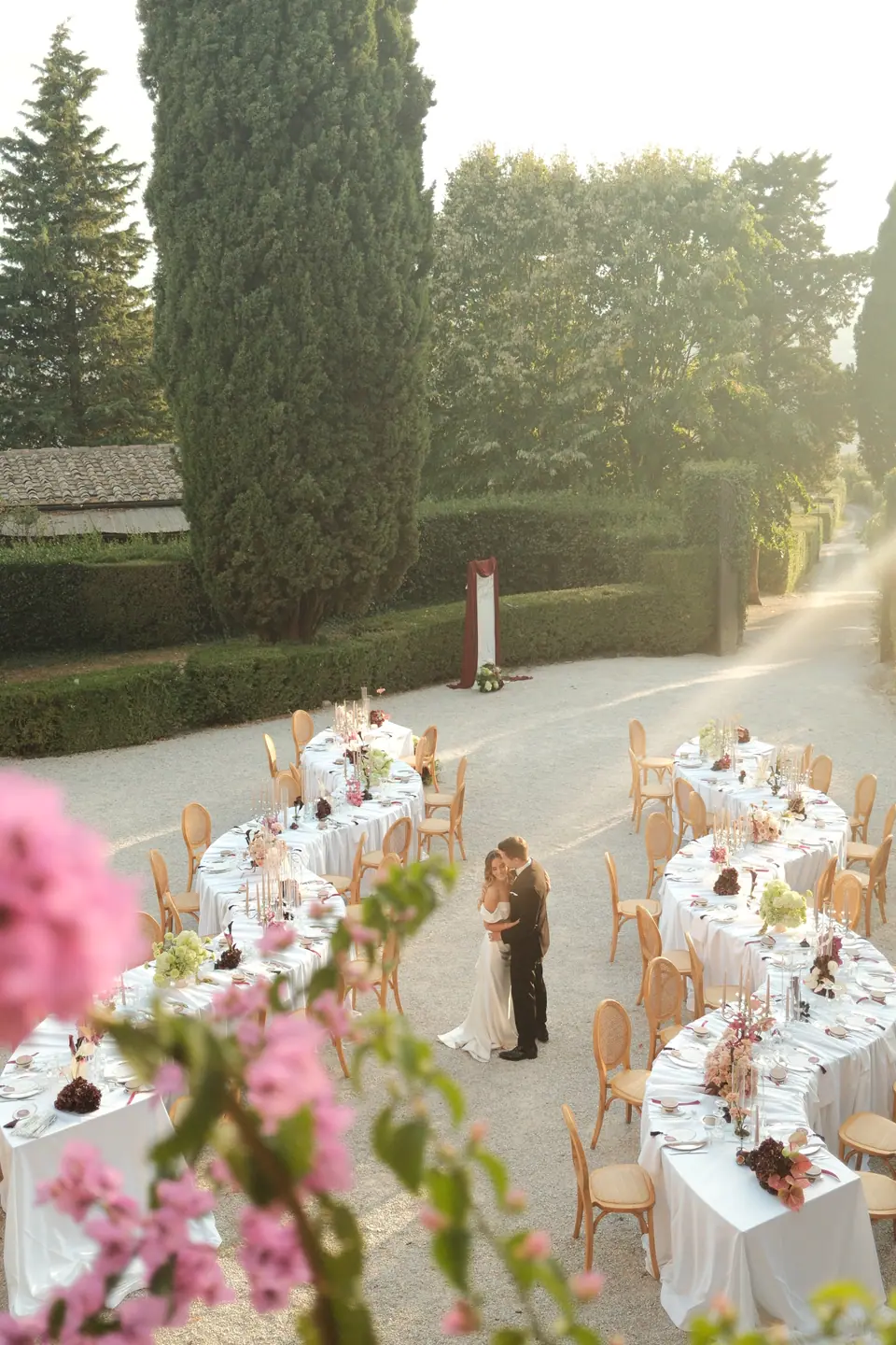 Ana and Silviu among the dinner tables, seen from above through pink flowers