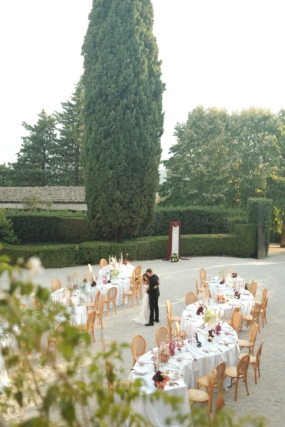 The couple standing among the set tables, seen from a terrace above