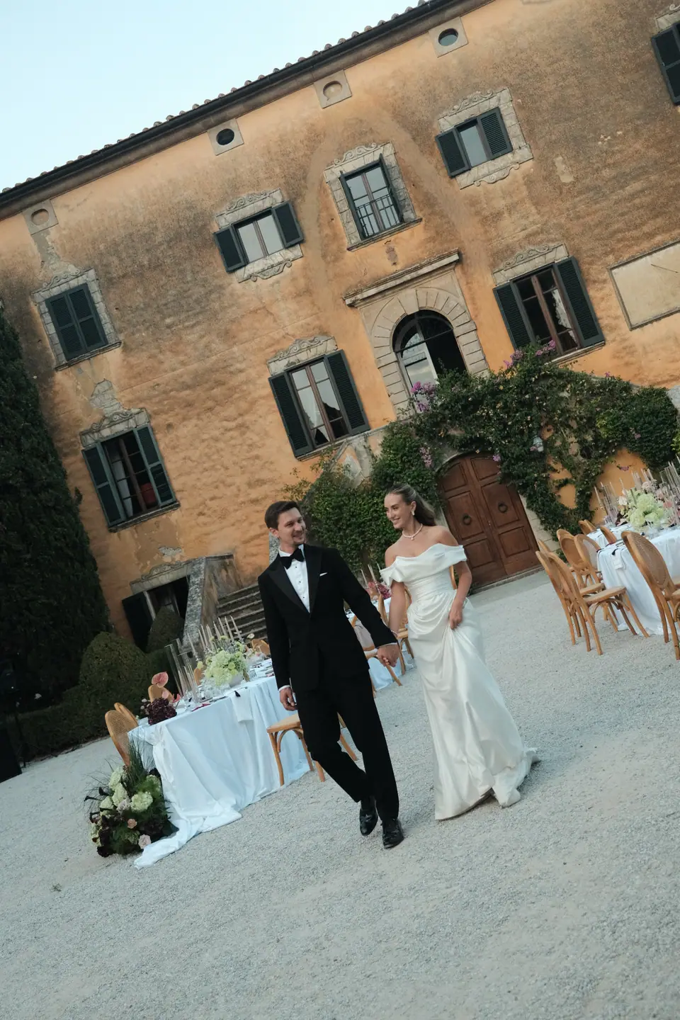 Ana and Silviu crossing the courtyard in front of the villa’s ochre façade