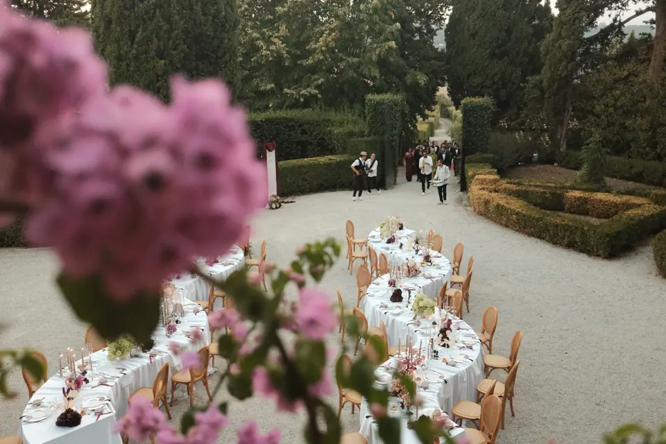 Pink flowers framing long dinner tables set in the villa garden