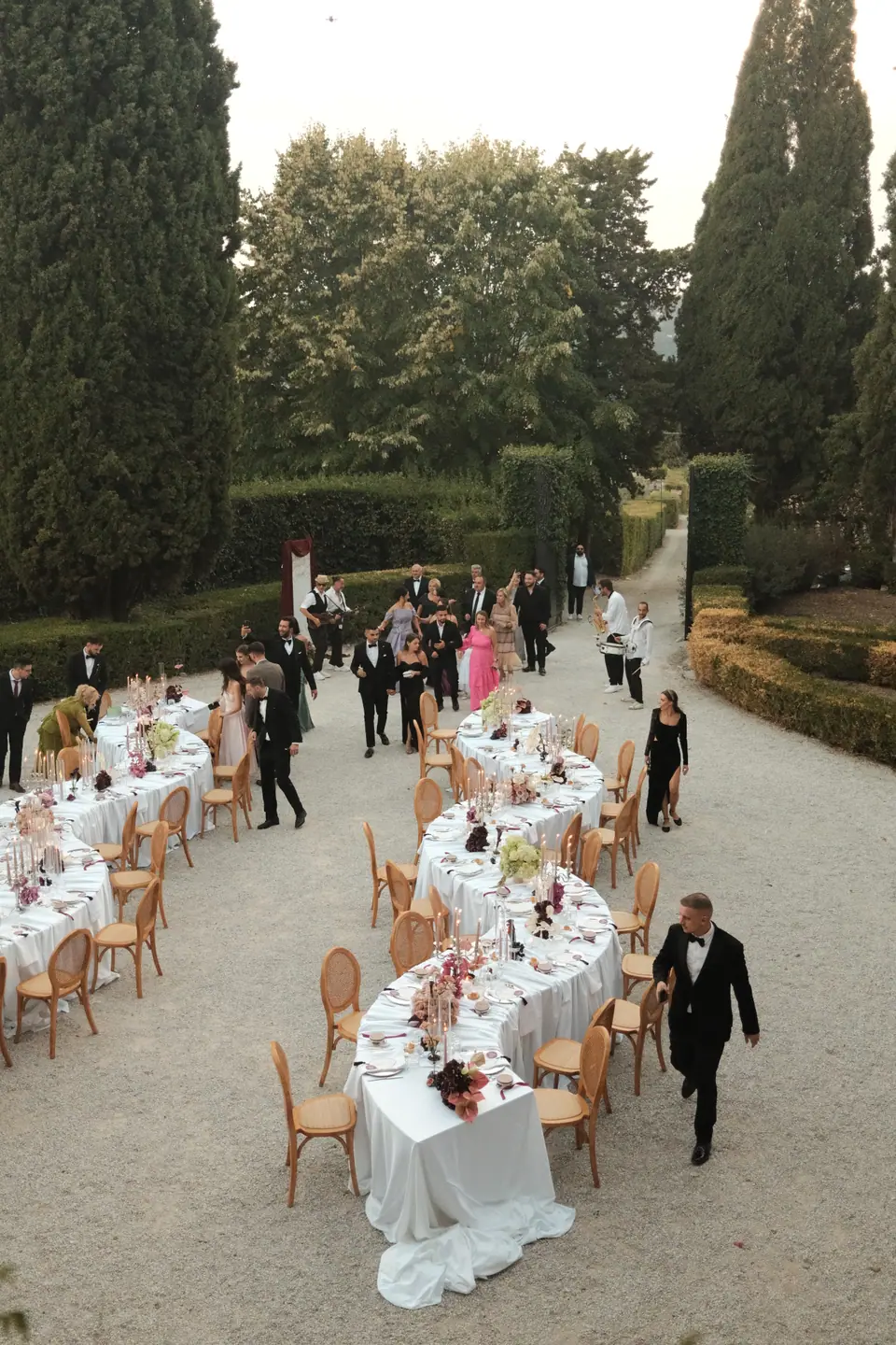 Guests arriving at the courtyard dinner along the hedged path