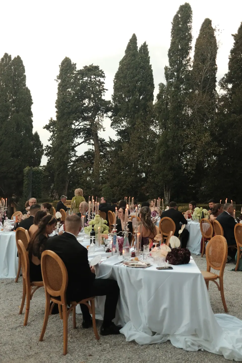 Guests settling in at the long tables under the cypresses