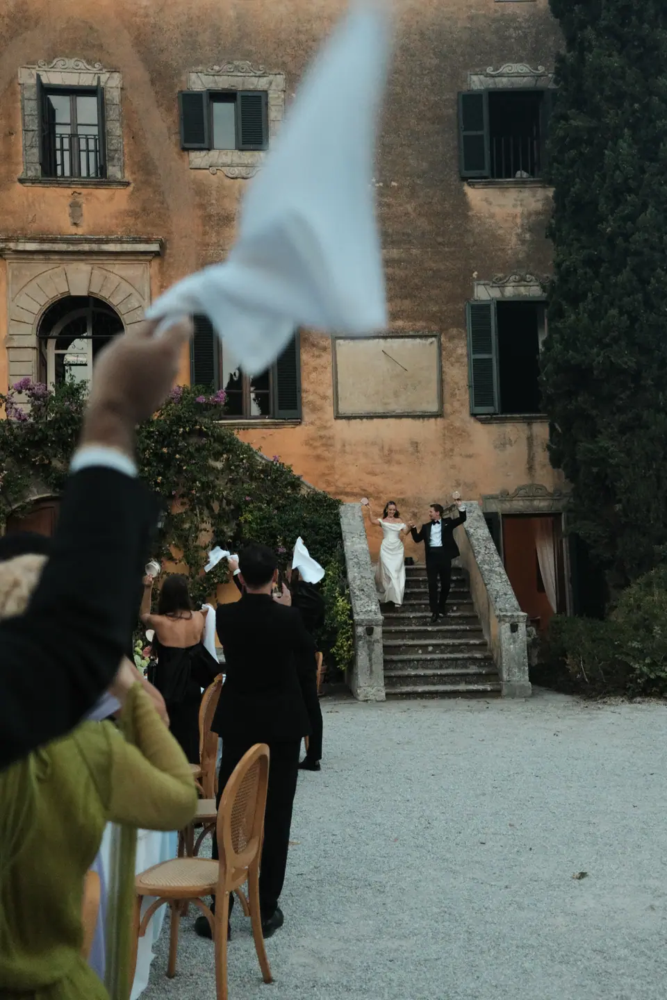Guests waving napkins as Ana and Silviu come down the villa steps