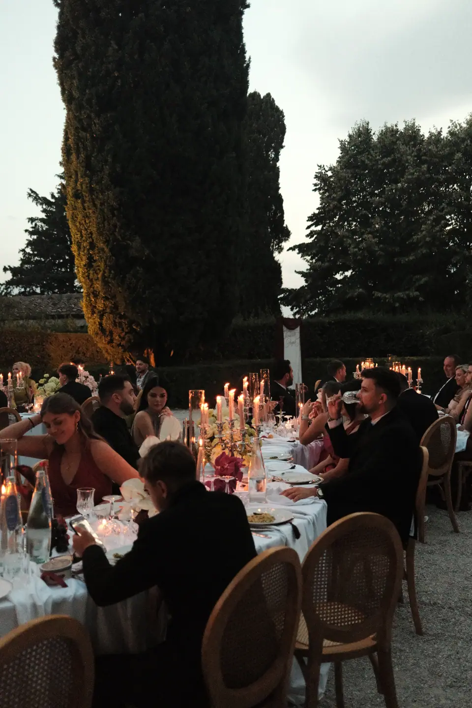 Guests at candlelit tables as night falls over the courtyard