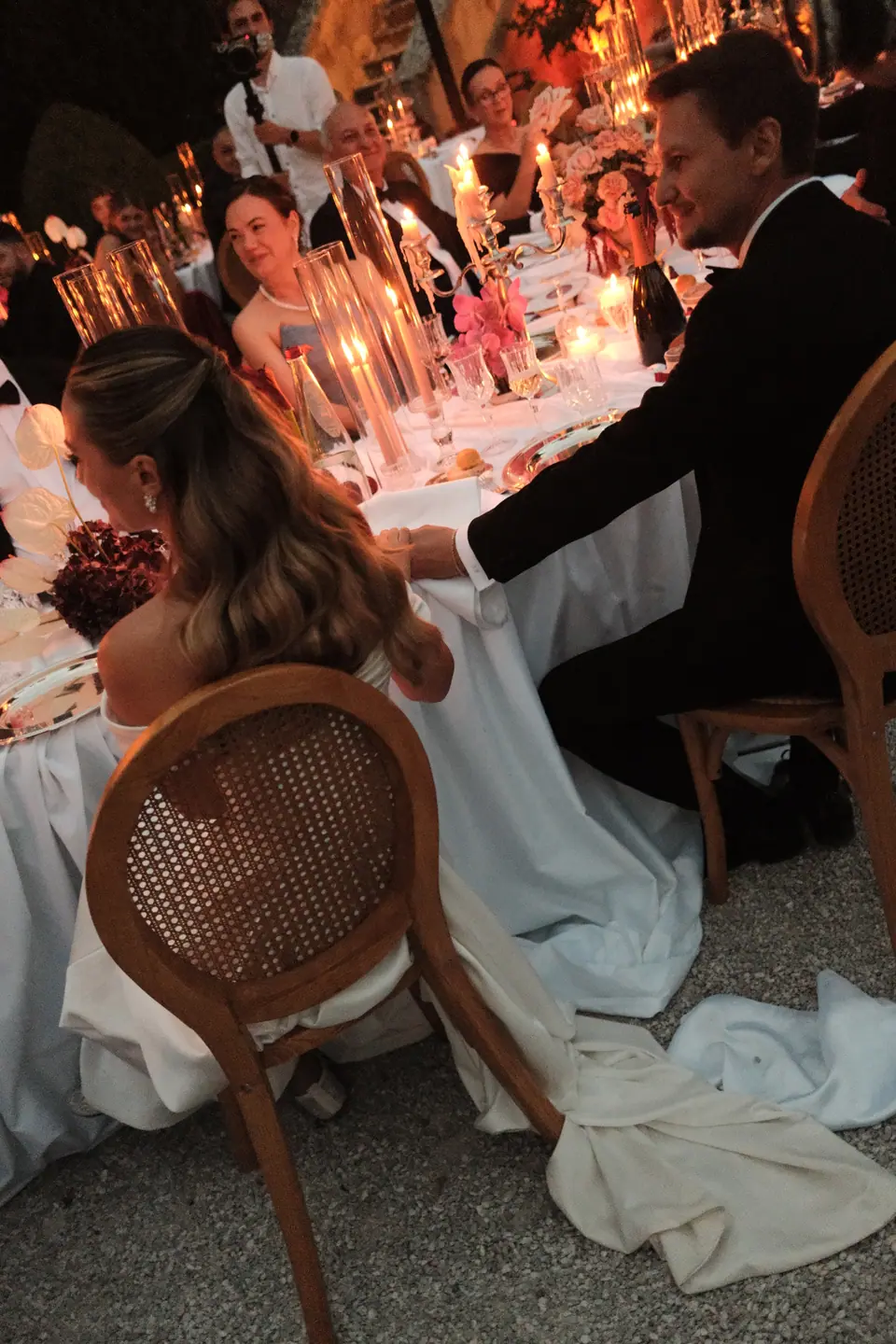 Ana at the candlelit table, her gown trailing over the gravel