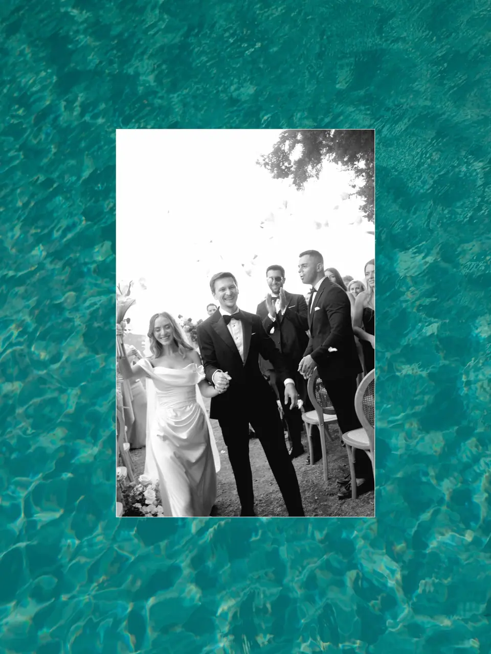 Black and white photograph of the couple walking back up the aisle, framed in pool water