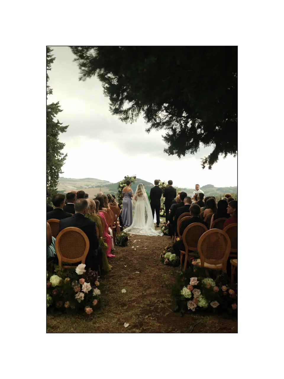 The garden ceremony seen from under a tree, guests in rattan chairs