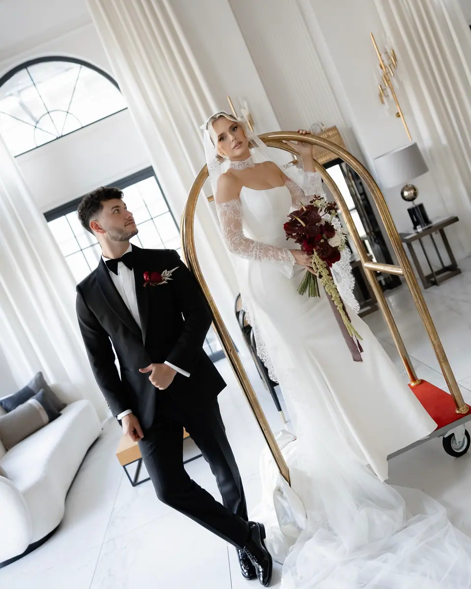 Bogdan in a black tuxedo beside Andreea in her lace gown, holding a red bouquet