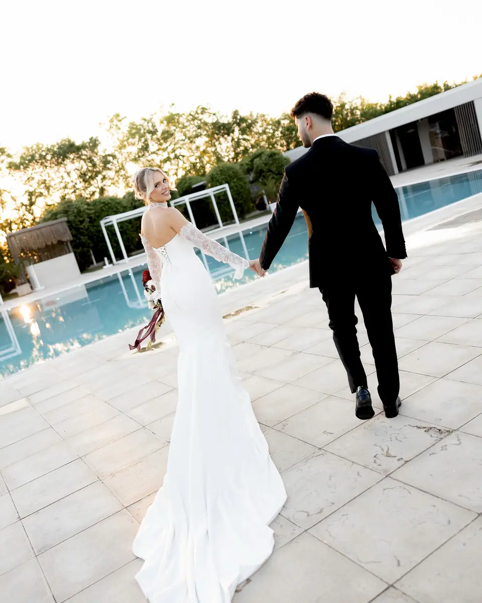 Andreea and Bogdan walking hand in hand beside the pool