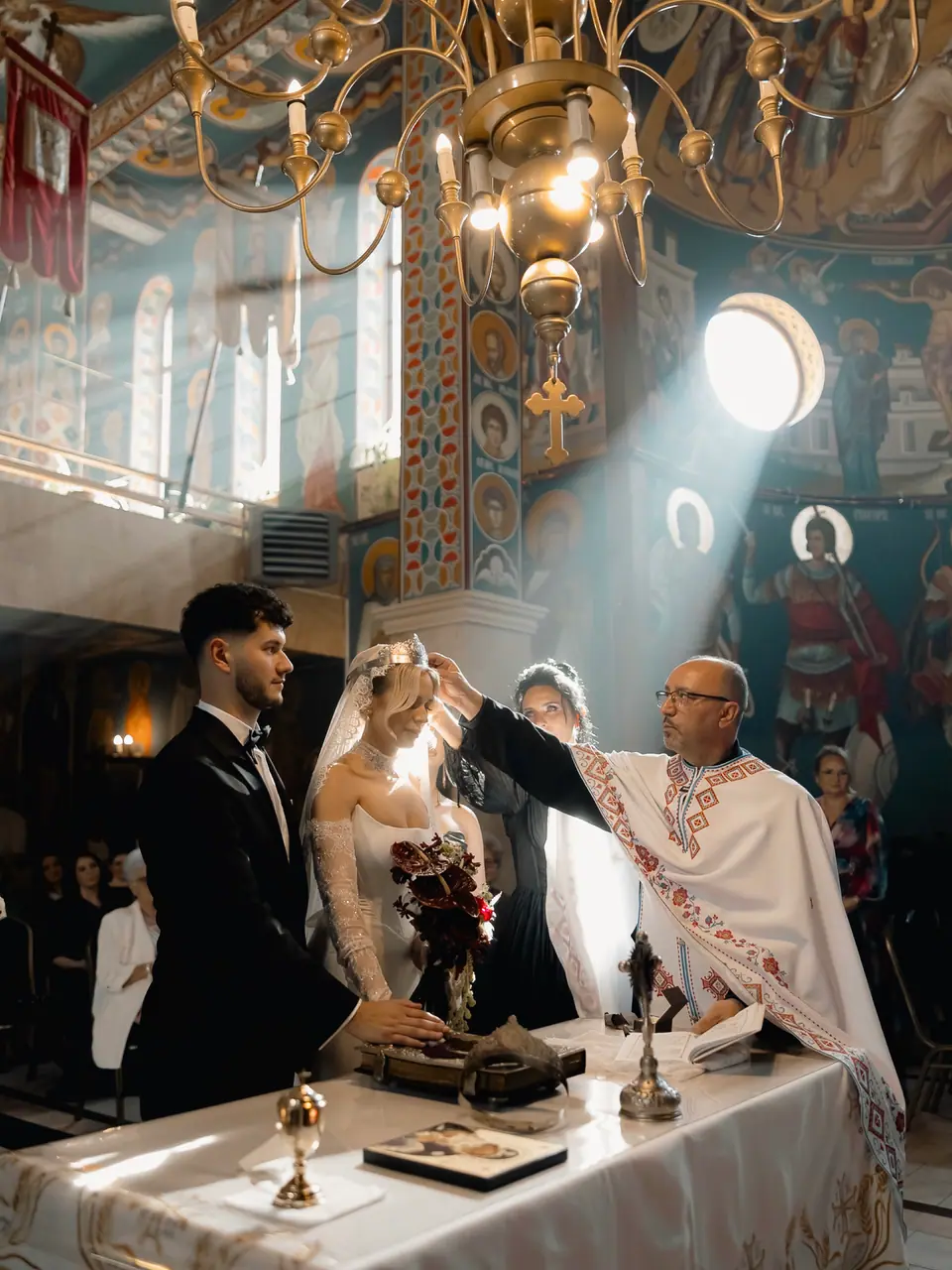 Light streaming across Andreea and Bogdan at the altar during the Orthodox ceremony