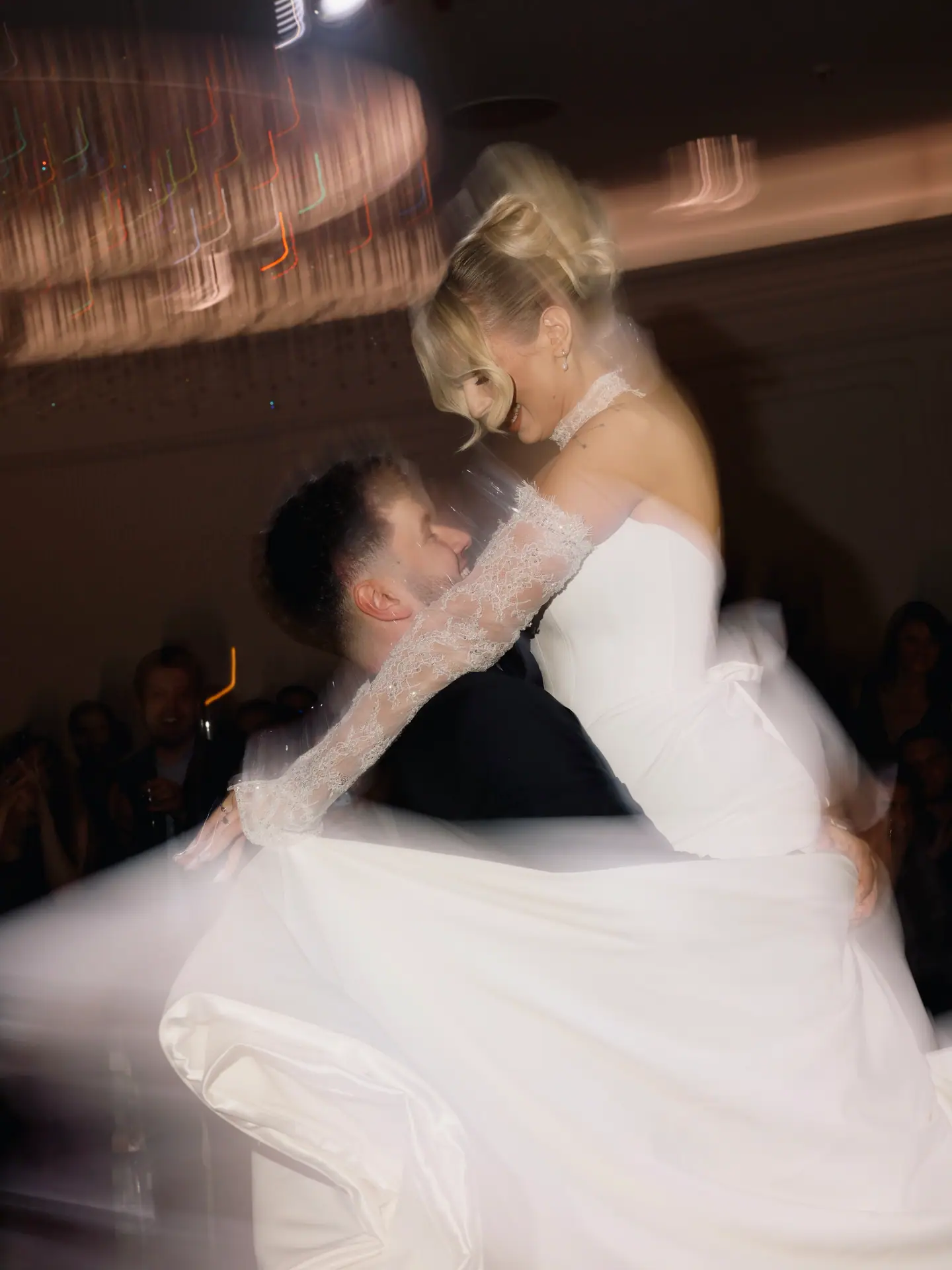 Bogdan lifting Andreea into a spin on the dance floor, the lights blurring around them