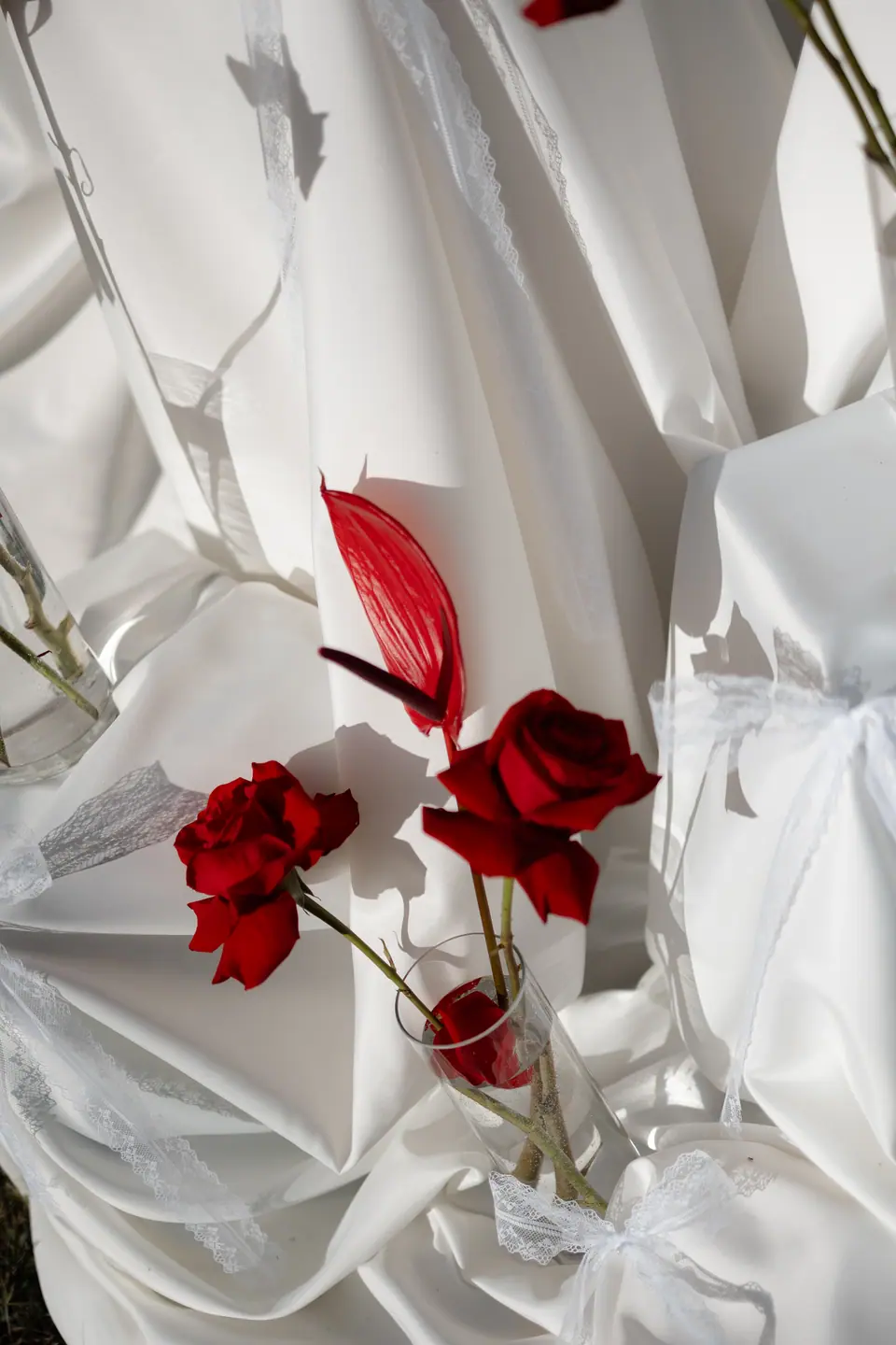 Red roses tucked into draped white fabric on the head table