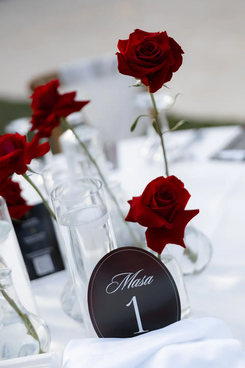 A table number reading “Masa 1” among single red roses
