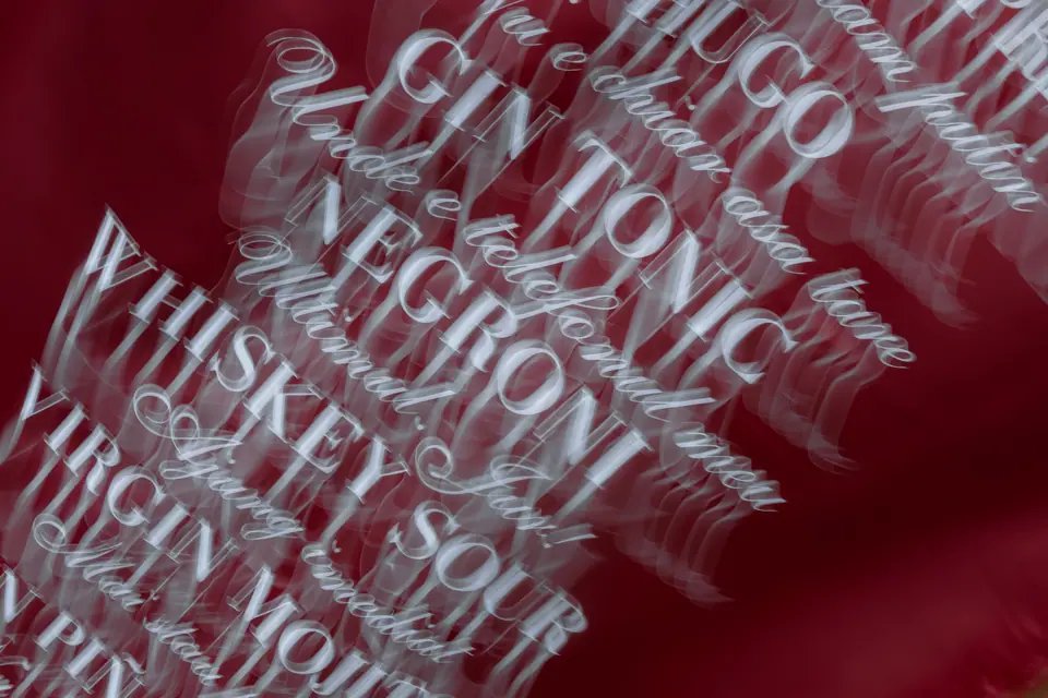 A drinks menu of Hugo, gin tonic and negroni printed on clear acrylic over red