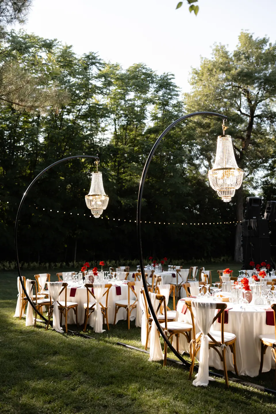 Two chandeliers on curved stands above the dinner tables on the lawn