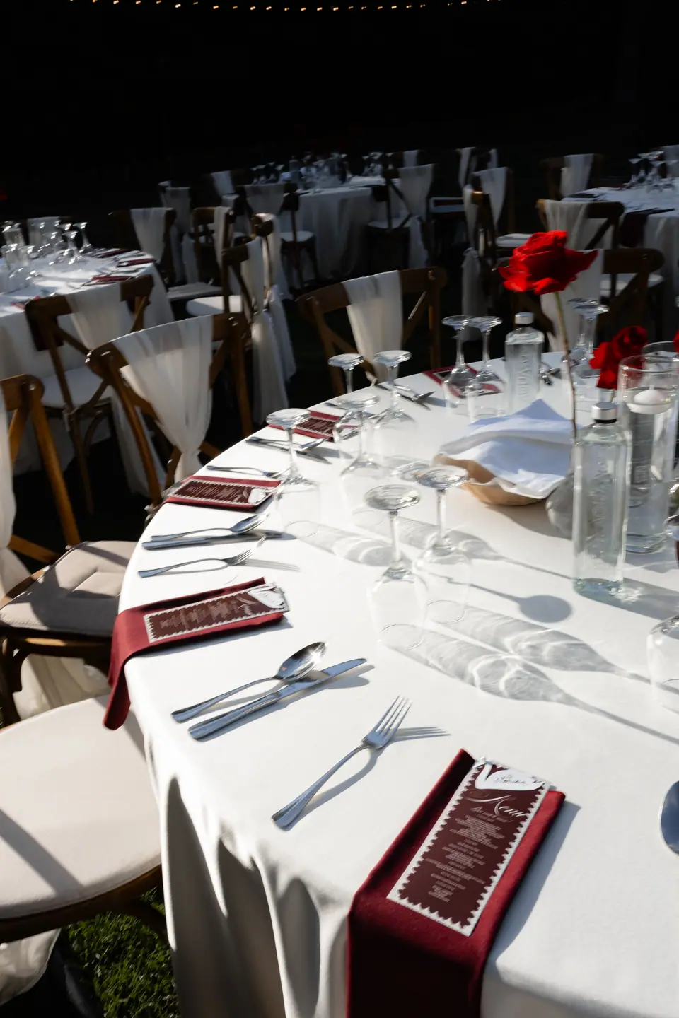 A round table set with burgundy napkins and red roses