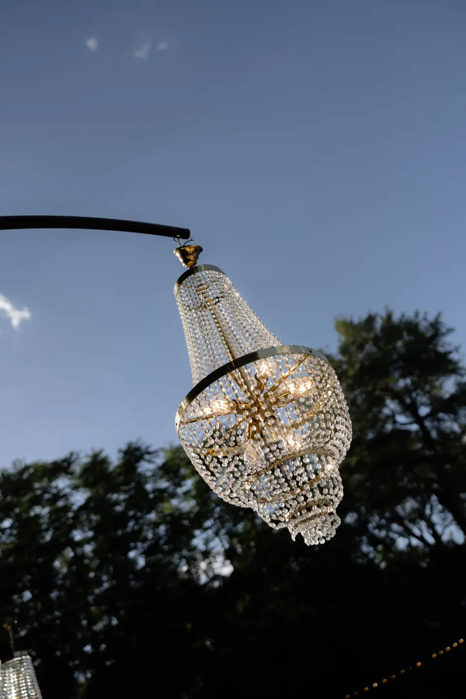 A crystal chandelier against blue sky beneath the trees