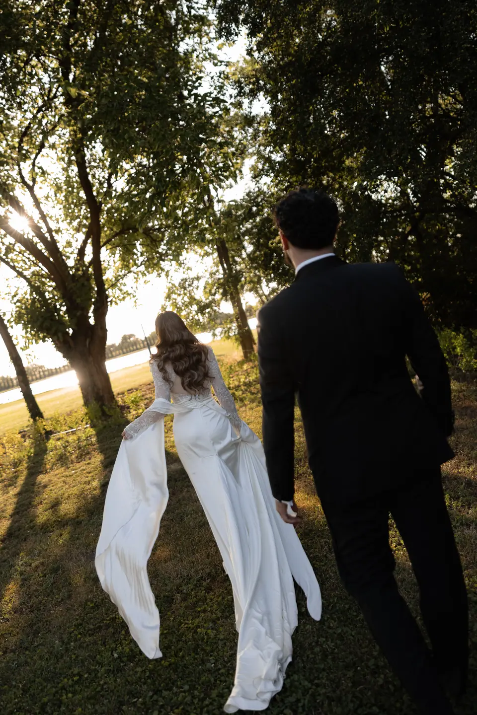 Bianca and Bogdan walking away across the grass into the evening sun