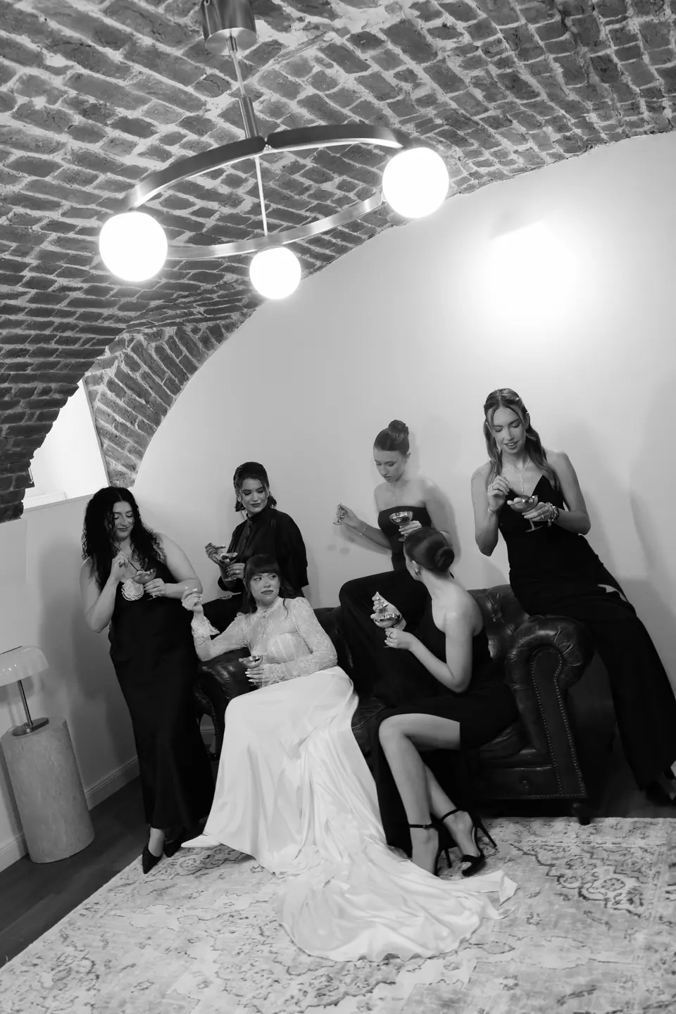Black and white photograph of Bianca and her bridesmaids eating tiramisu on the sofa