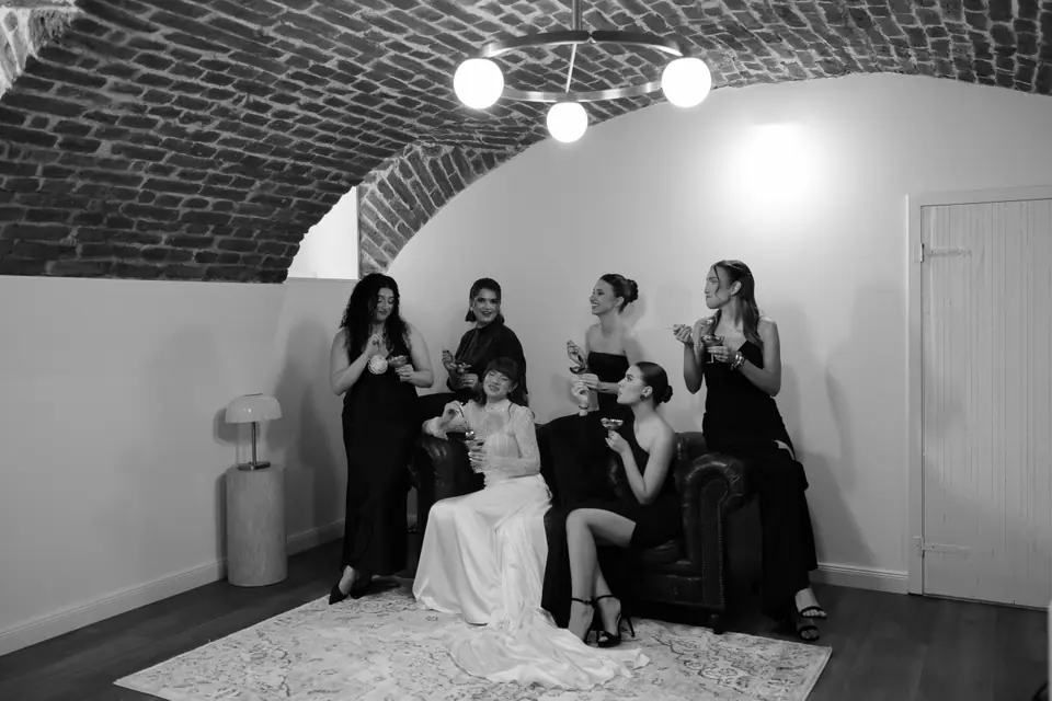 Black and white photograph of the bridesmaids gathered around Bianca on the sofa