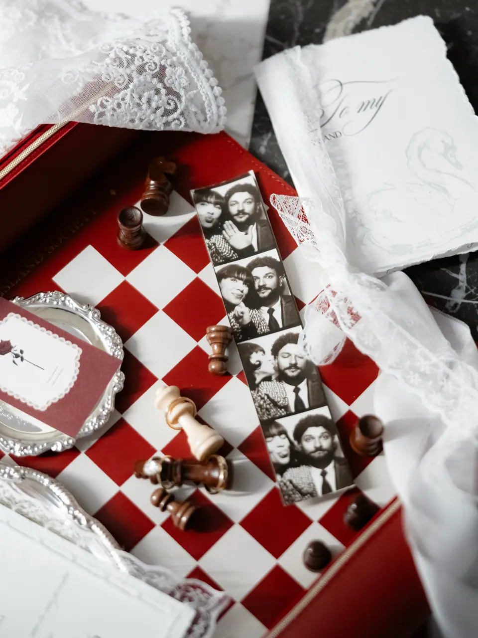 A red and white chessboard with a photo-booth strip, lace and a handwritten note