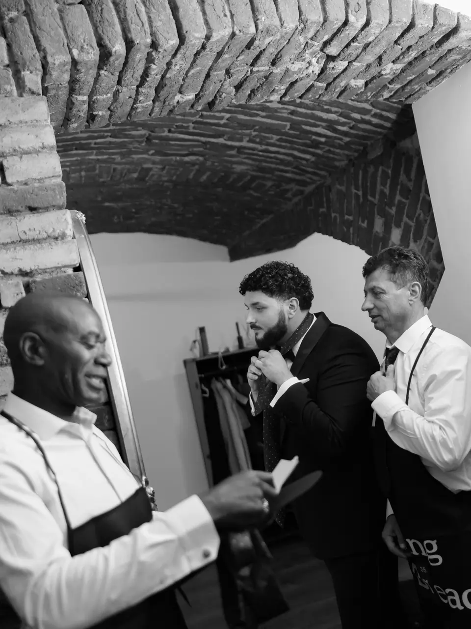 Black and white photograph of Bogdan getting ready with two friends in aprons