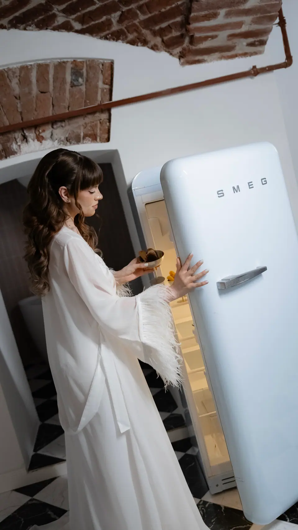Bianca in her feathered robe opening the blue Smeg fridge