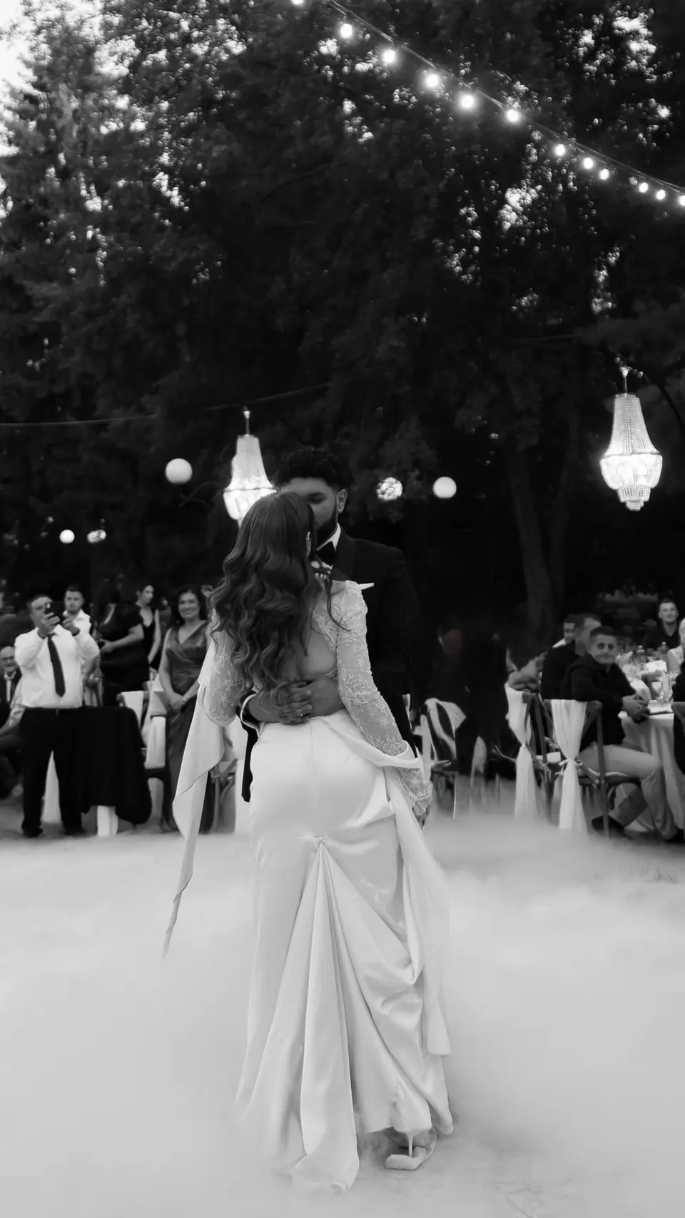 Black and white photograph of the first dance in low smoke under chandeliers